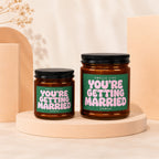 Two amber glass candles with green labels that say "Smells Like You're Getting Married".