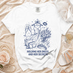 White t-shirt with a navy blue graphic of a dress, champagne, bouquet, crown, and text.