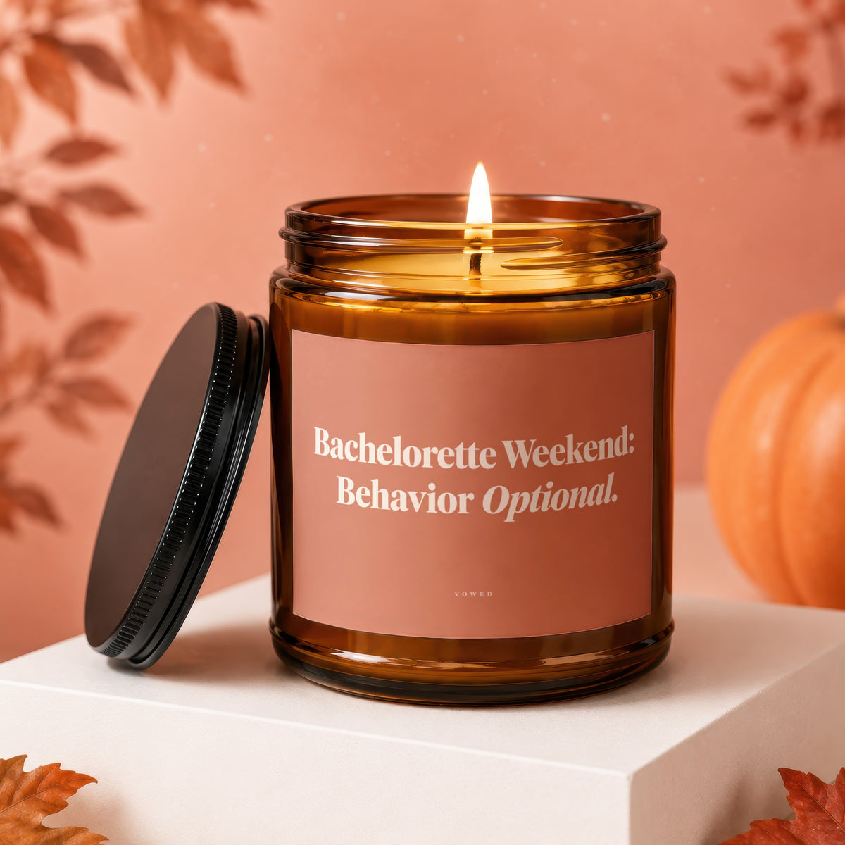 Amber glass candle with lit wick, reads "Bachelorette Weekend: Behavior Optional."