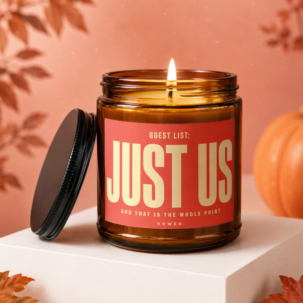 Amber jar candle with lit flame and "GUEST LIST: JUST US" label.