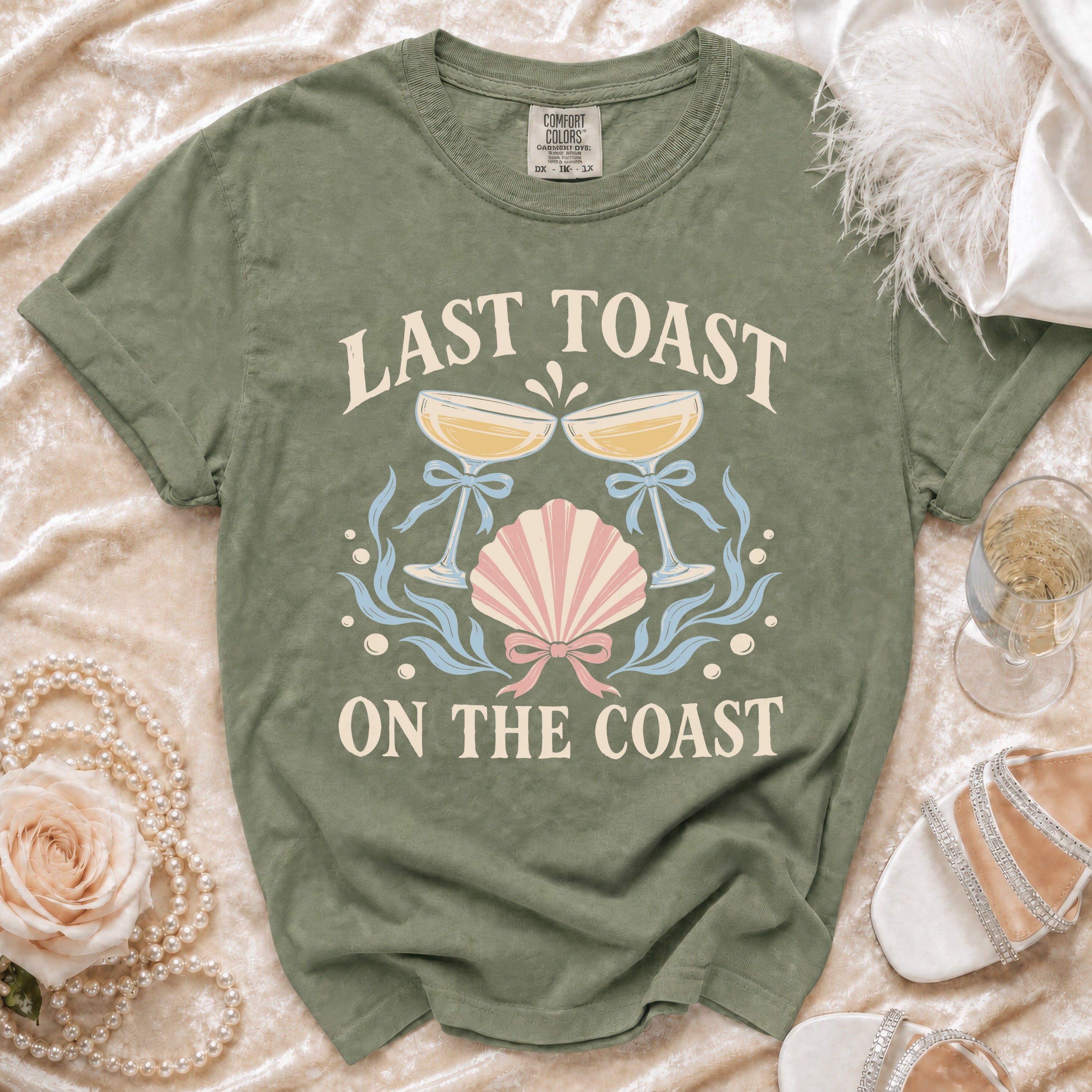 Green t-shirt with "Last Toast On The Coast" text and champagne glasses graphic.