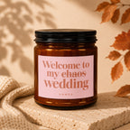 Amber candle with a pink label that says "Welcome to my chaos wedding VOWED".