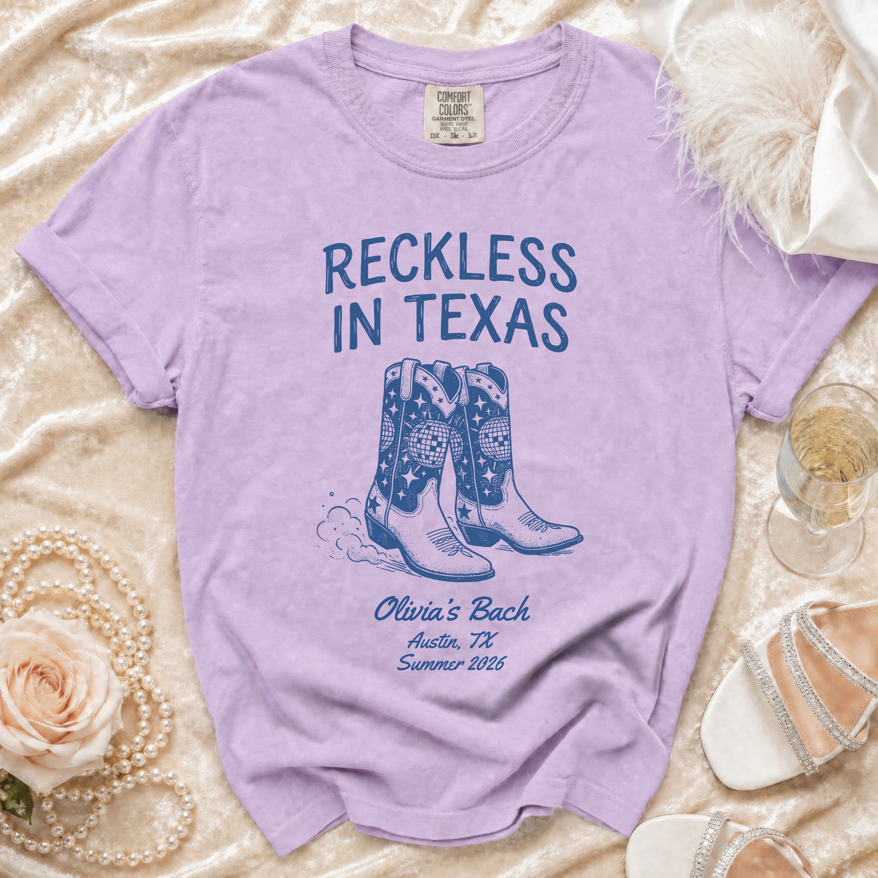 Lavender t-shirt with "Reckless in Texas" and cowboy boots graphic.