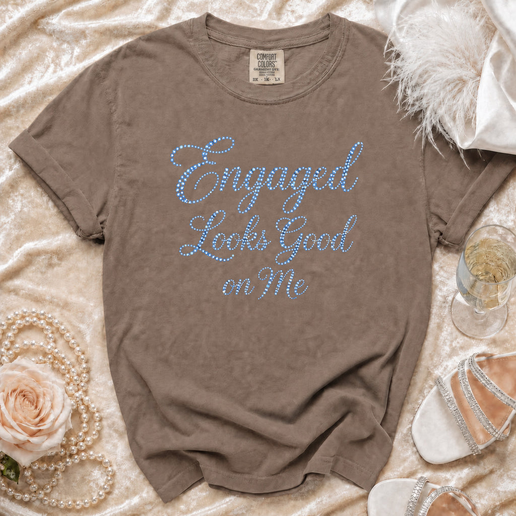 Brown t-shirt with blue jeweled text "Engaged Looks Good on Me".