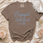 Brown t-shirt with blue jeweled text "Engaged Looks Good on Me".