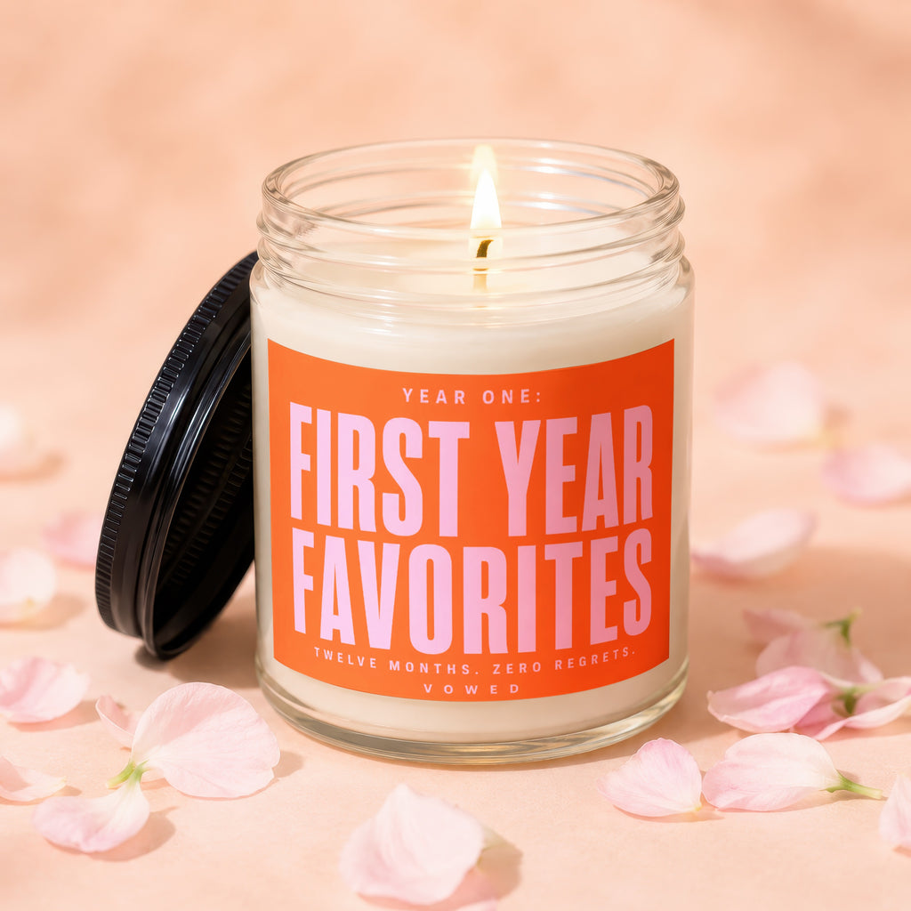 Glass candle with orange label reading "First Year Favorites" with pink text.