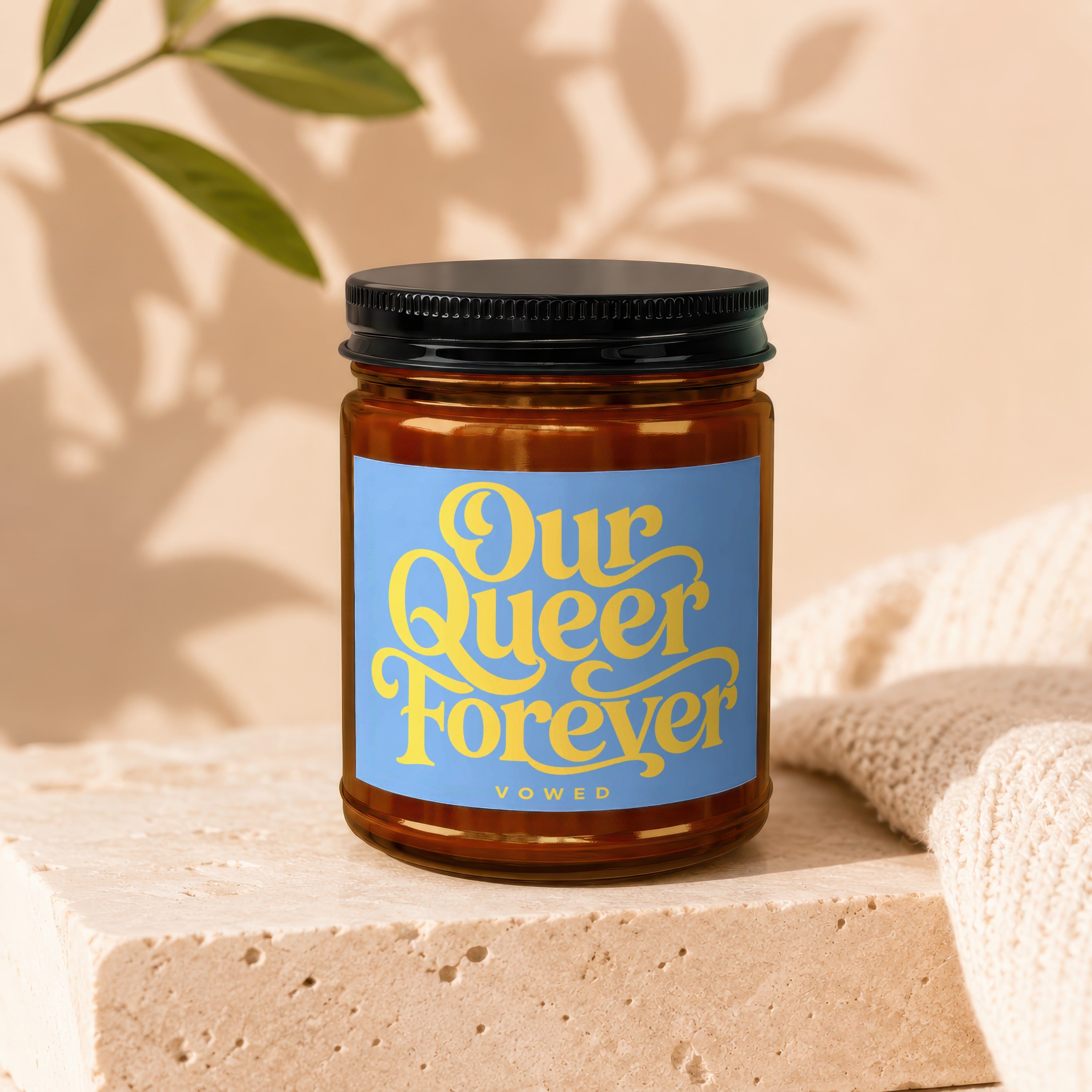 Candle with blue label reading "Our Queer Forever," VOWED.