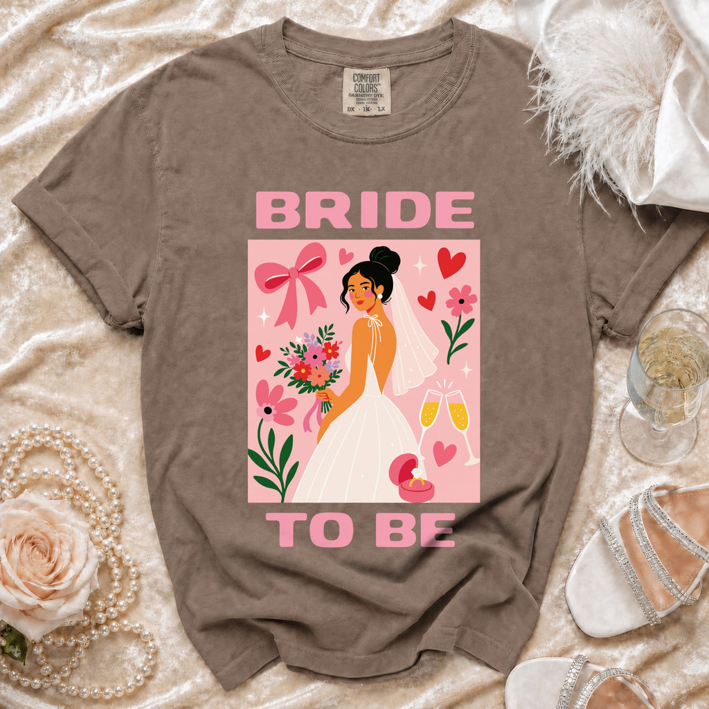 Bride To Be graphic on a t-shirt with a bride, flowers, and champagne.