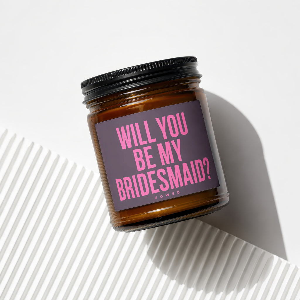 Candle in amber jar with black lid, "Will you be my bridesmaid?" in pink text.