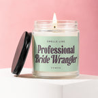 Lit candle with "Smells Like Professional Bride Wrangler Vowed" text on a pale green label.