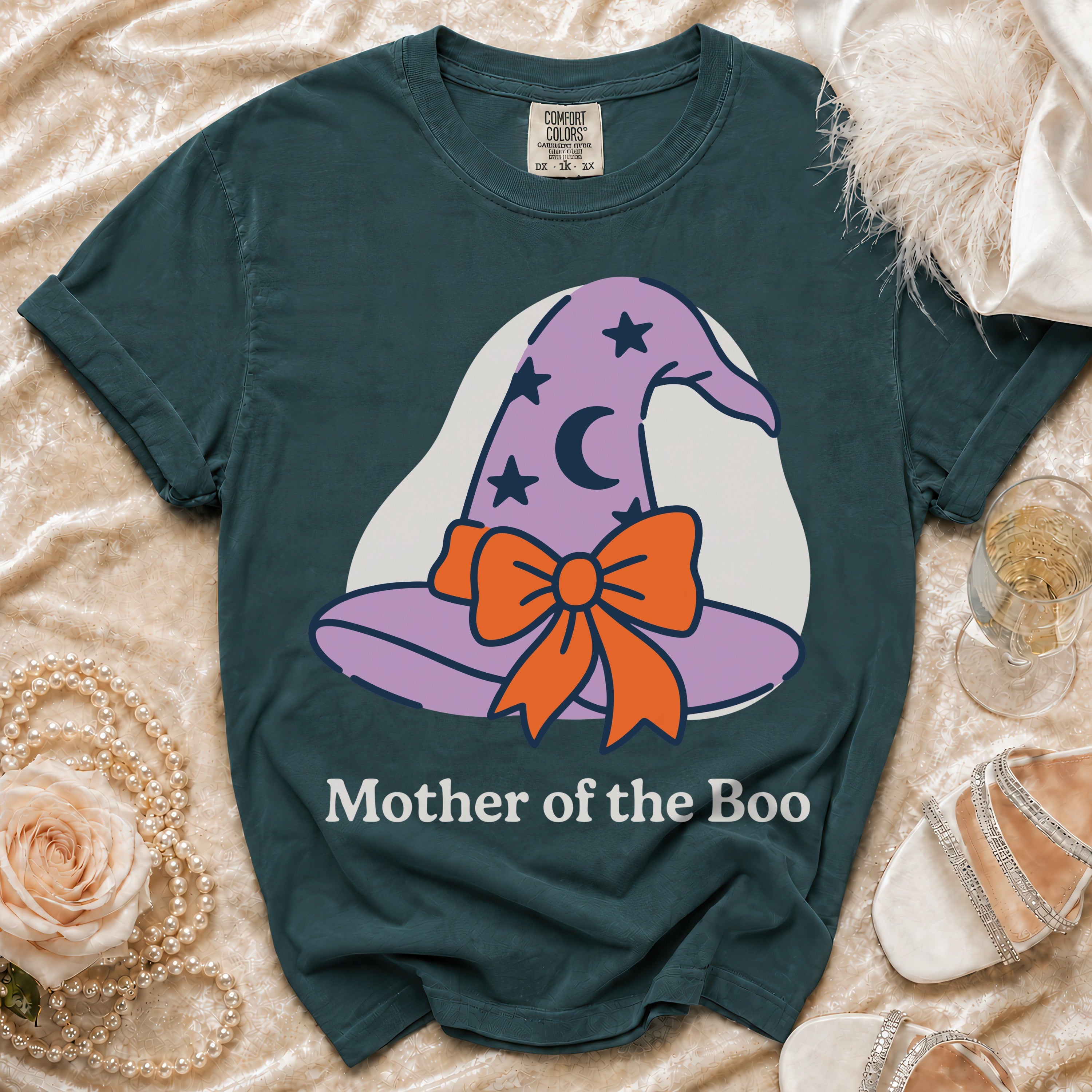 Dark teal t-shirt with a purple witch hat graphic and text "Mother of the Boo".
