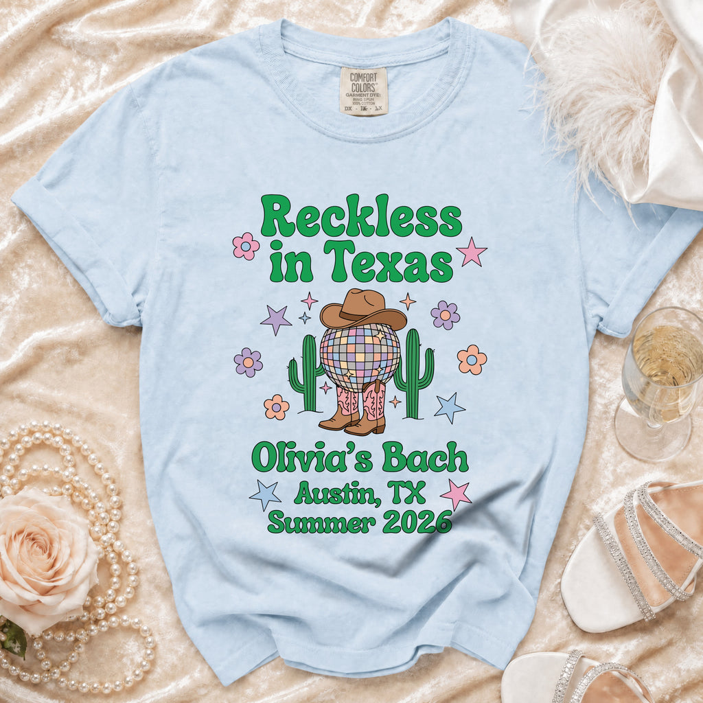 Light blue t-shirt with "Reckless in Texas" and "Olivia's Bach Austin, TX Summer 2026" text.