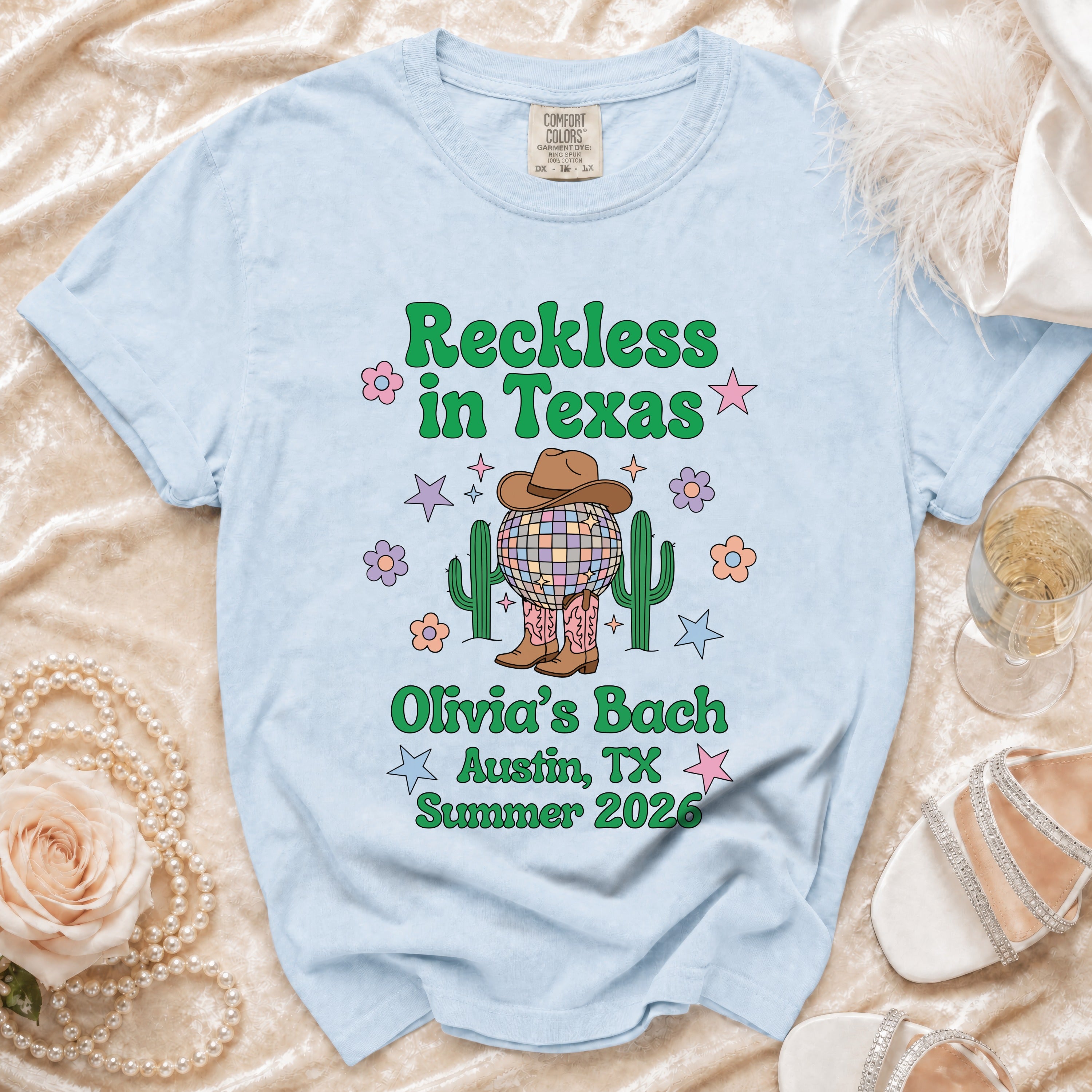 Light blue t-shirt with "Reckless in Texas" and "Olivia's Bach Austin, TX Summer 2026" text.