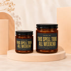 Two amber glass candles with black lids, labeled "This Spell Took All Weekend."