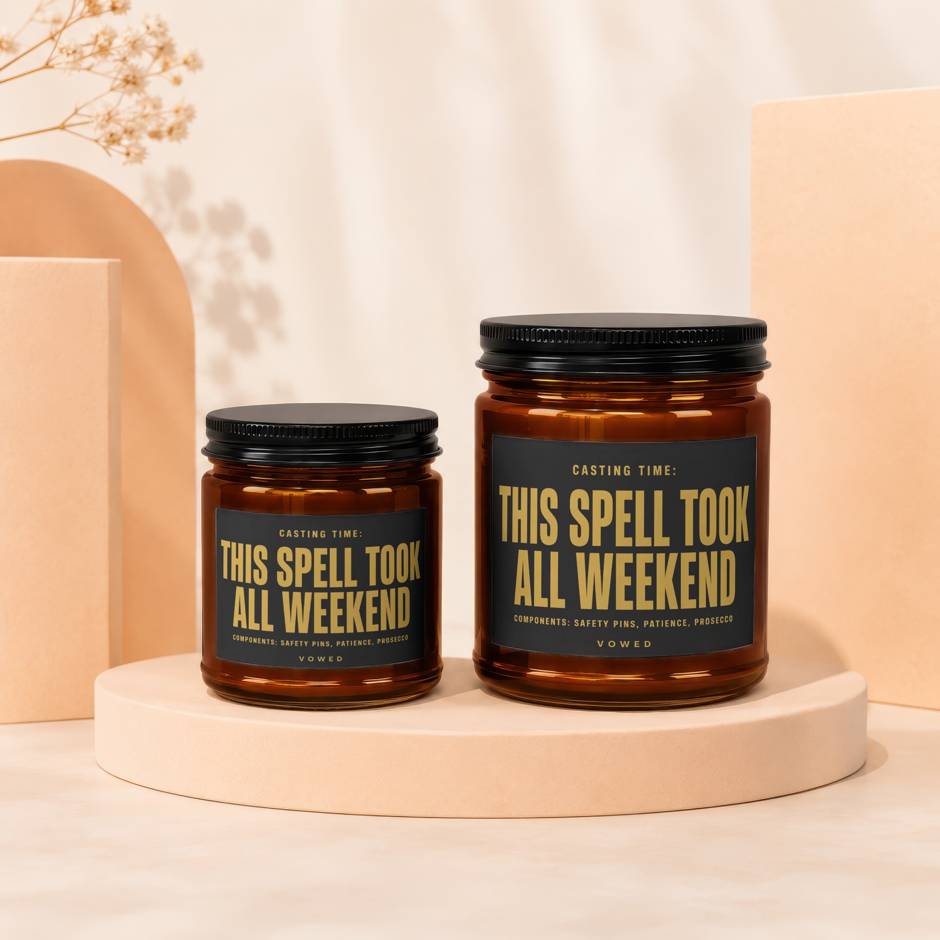 Two amber glass candles with black lids, labeled "This Spell Took All Weekend."