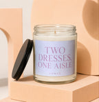 Glass jar candle with black lid, reading "TWO DRESSES, ONE AISLE" and "VOWED."