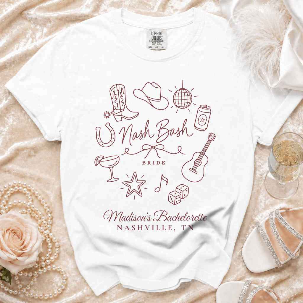 White t-shirt featuring a maroon bachelorette design with western icons, Nashville text, and pearls nearby.