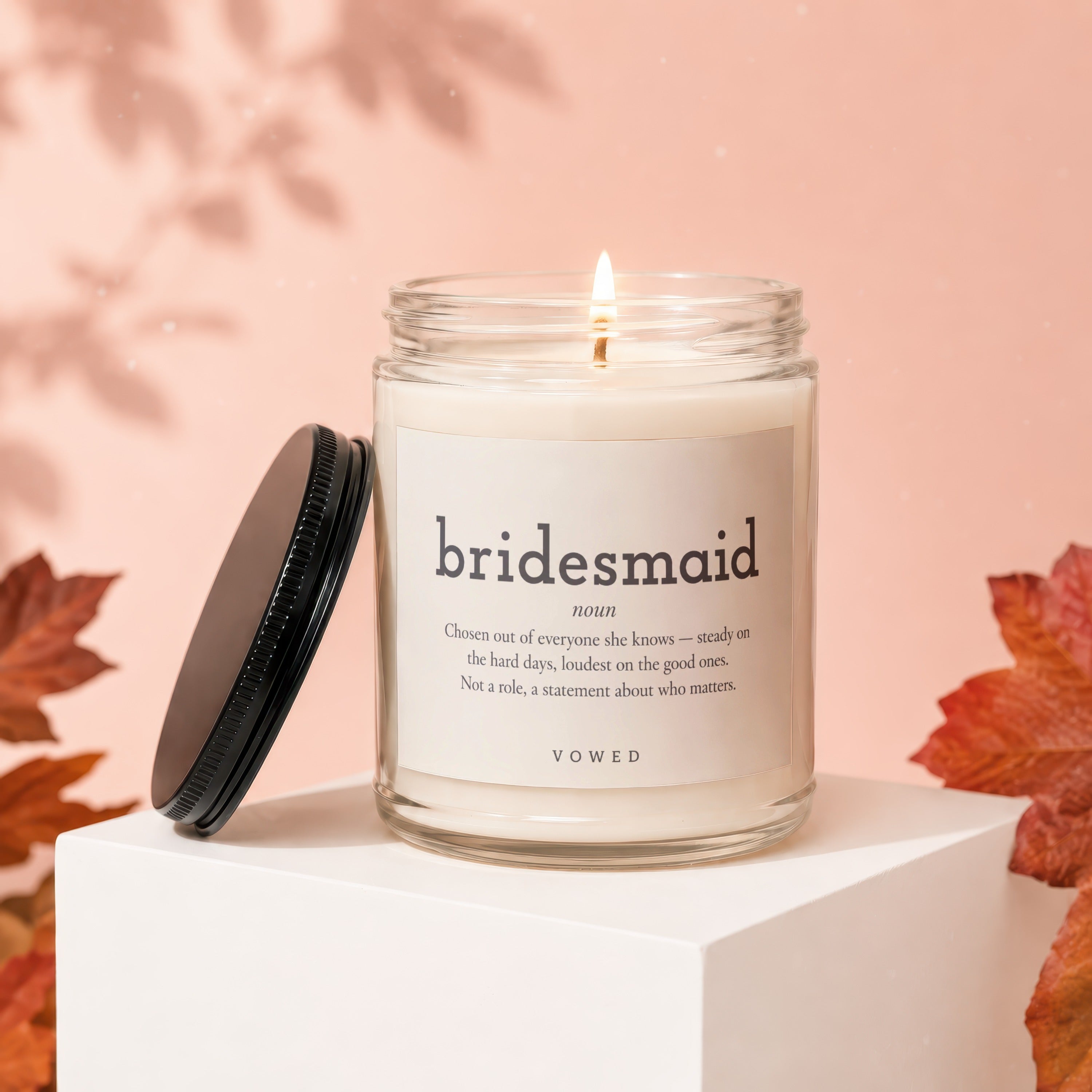 Candle labeled "bridesmaid" with definition, lit flame, and black lid displayed.
