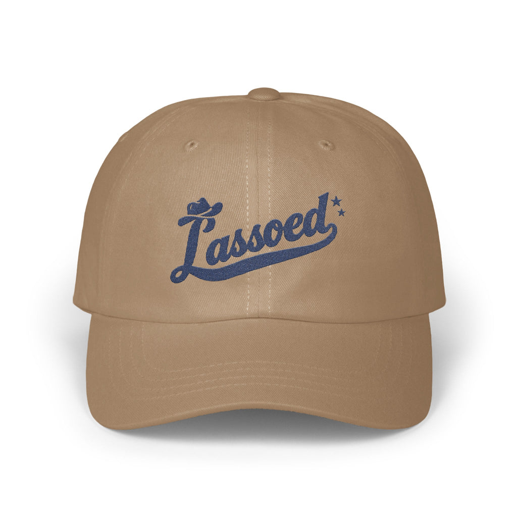 Tan baseball cap featuring blue embroidered cursive text reading Lassoed with two small stars.