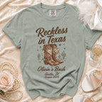 Comfort Colors t-shirt with "Reckless in Texas Olivia's Bach" design.
