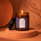Amber jar candle with lit flame and purple label for Ruth + Caleb.