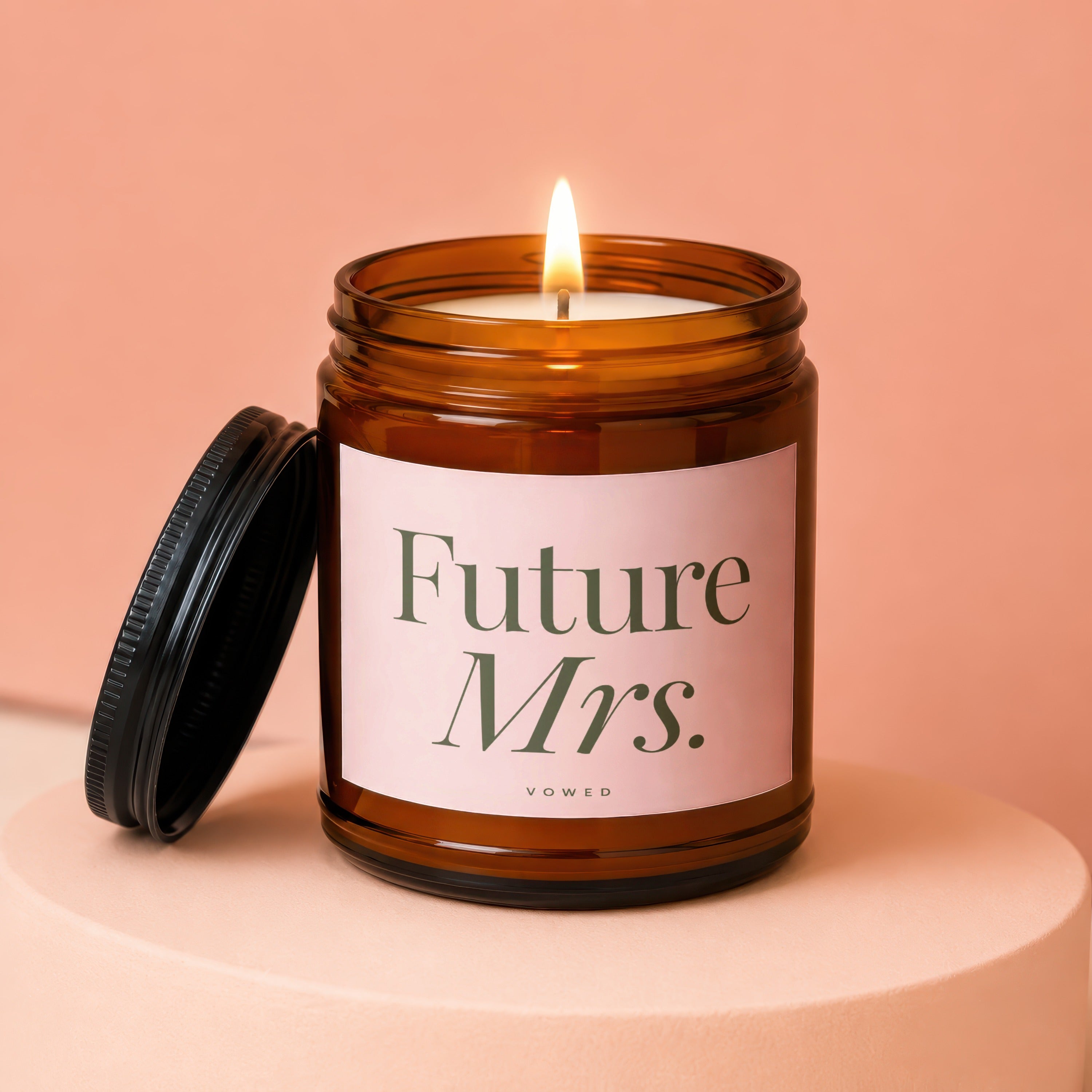 Candle reading "Future Mrs." with lid removed and lit flame.