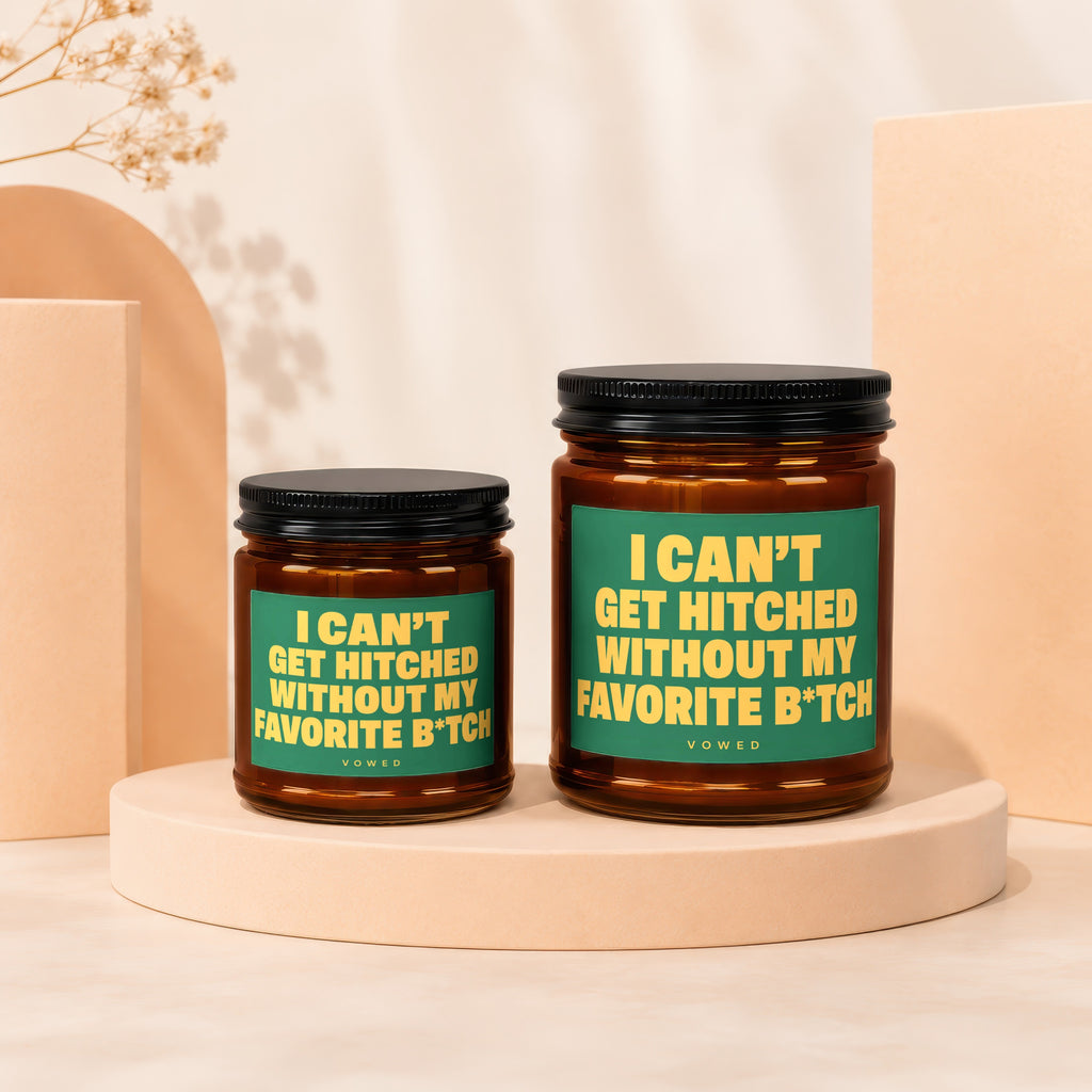 Two amber glass candles with black lids and green labels reading "I CAN'T GET HITCHED WITHOUT MY FAVORITE B*TCH".