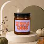 Amber jar candle on a pedestal with text "TWO BRIDES ARE BETTER THAN ONE".