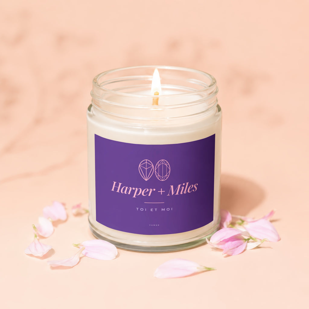 Harper + Miles "Toi et Moi" candle with lit wick on a light pink background.