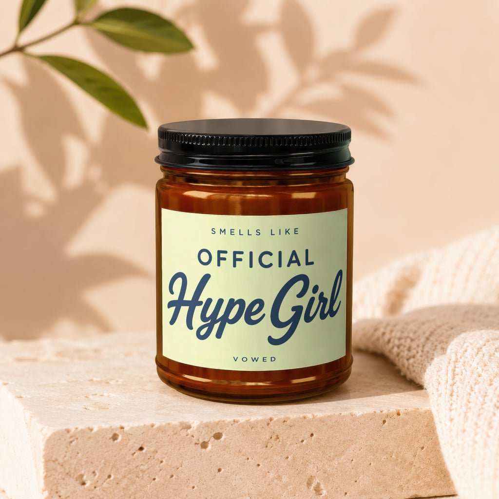 Amber candle in a jar with black lid, label reads "Official Hype Girl"