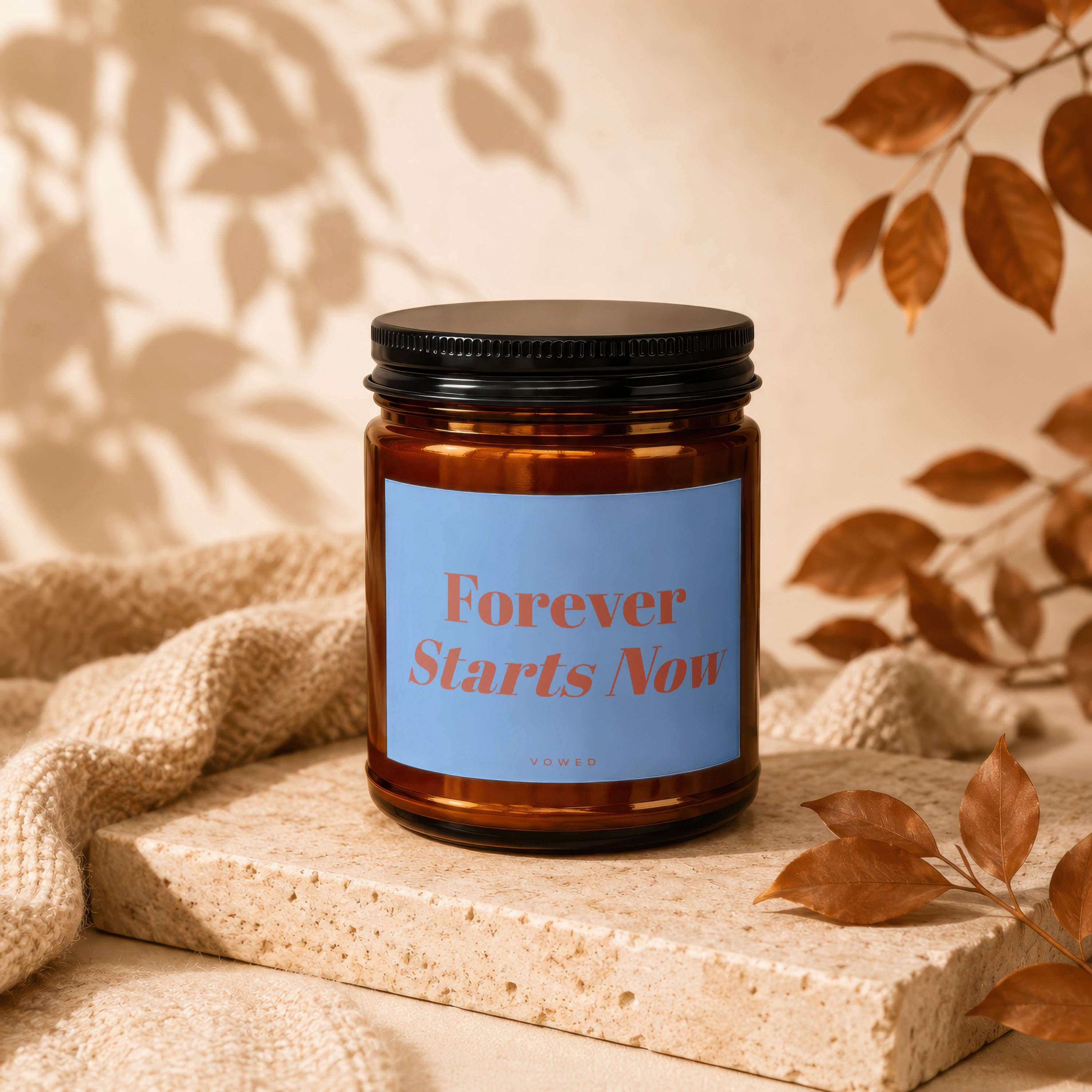 Amber candle jar with a black lid and a blue label reading "Forever Starts Now".
