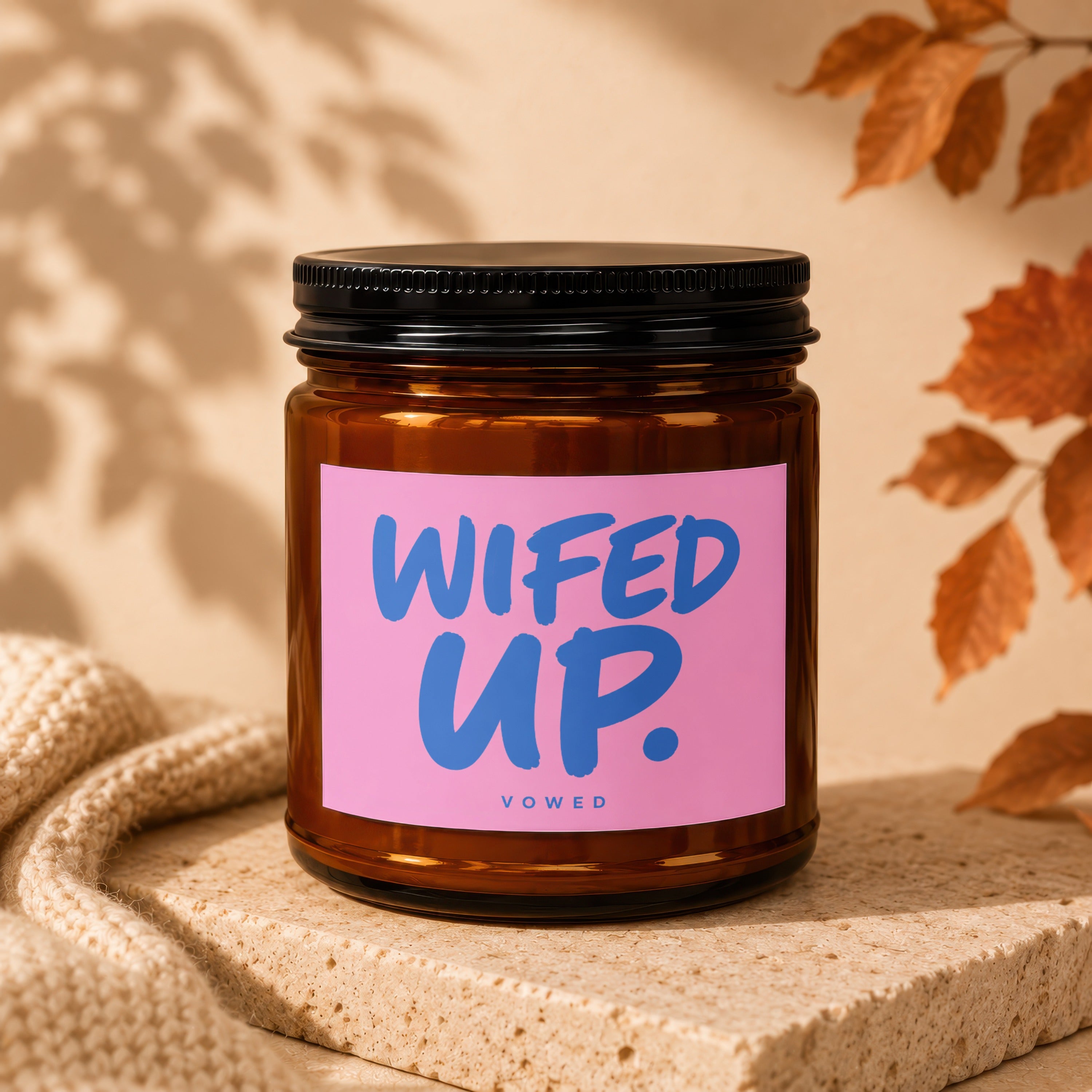 Brown glass jar candle with pink label that says "WIFED UP." VOWED.