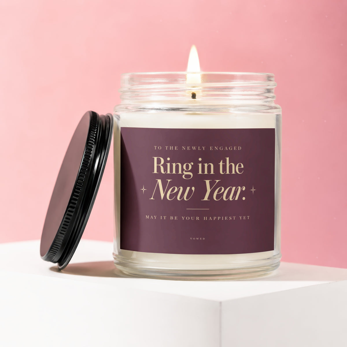 Glass jar candle with lid off, labeled "Ring in the New Year."