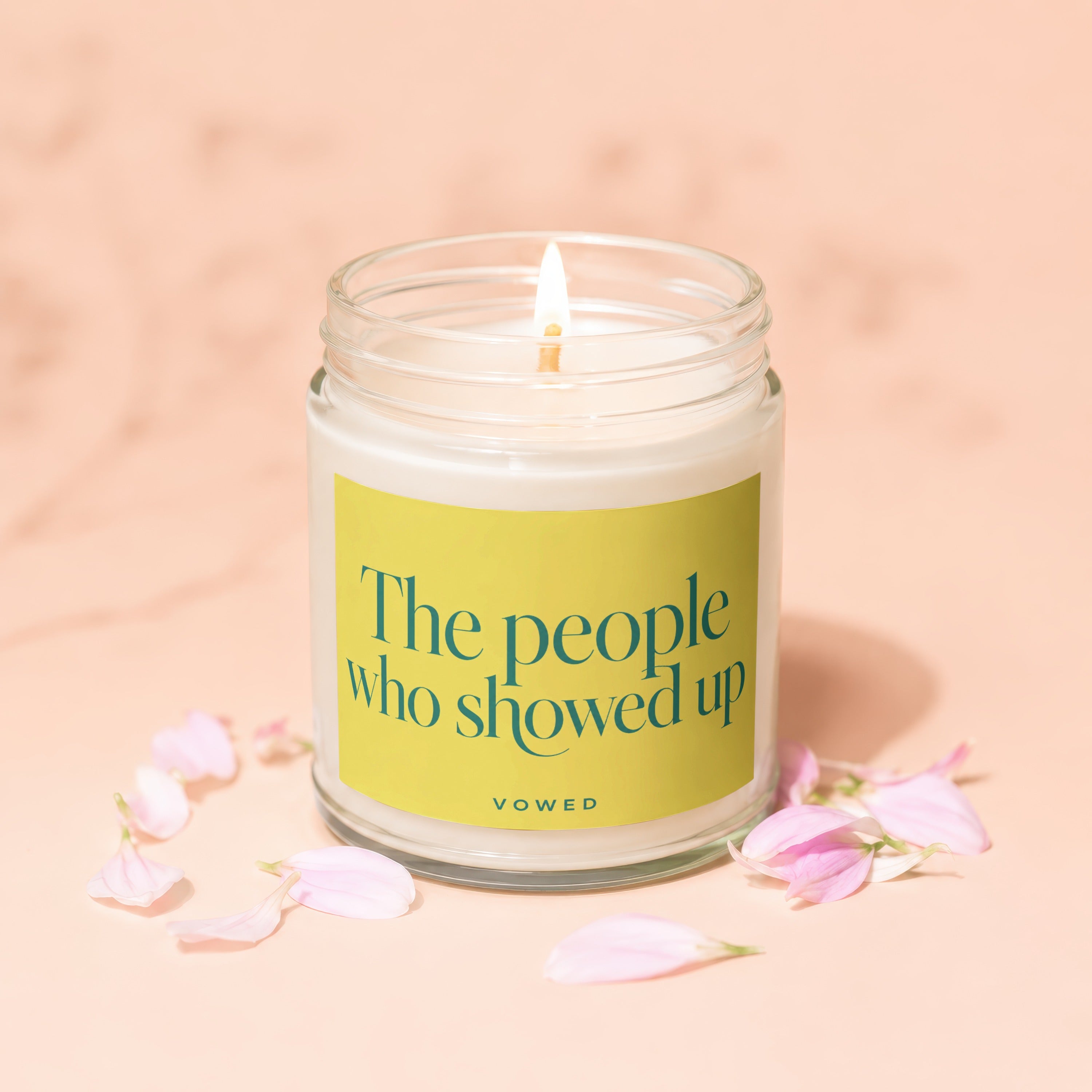 Lit candle in a glass jar with yellow label text "The people who showed up VOWED".