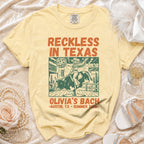 Yellow t-shirt with "Reckless in Texas" and "Olivia's Bach" designs.