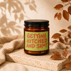 Amber candle with a green label reading "GETTING HITCHED AND SH*T".