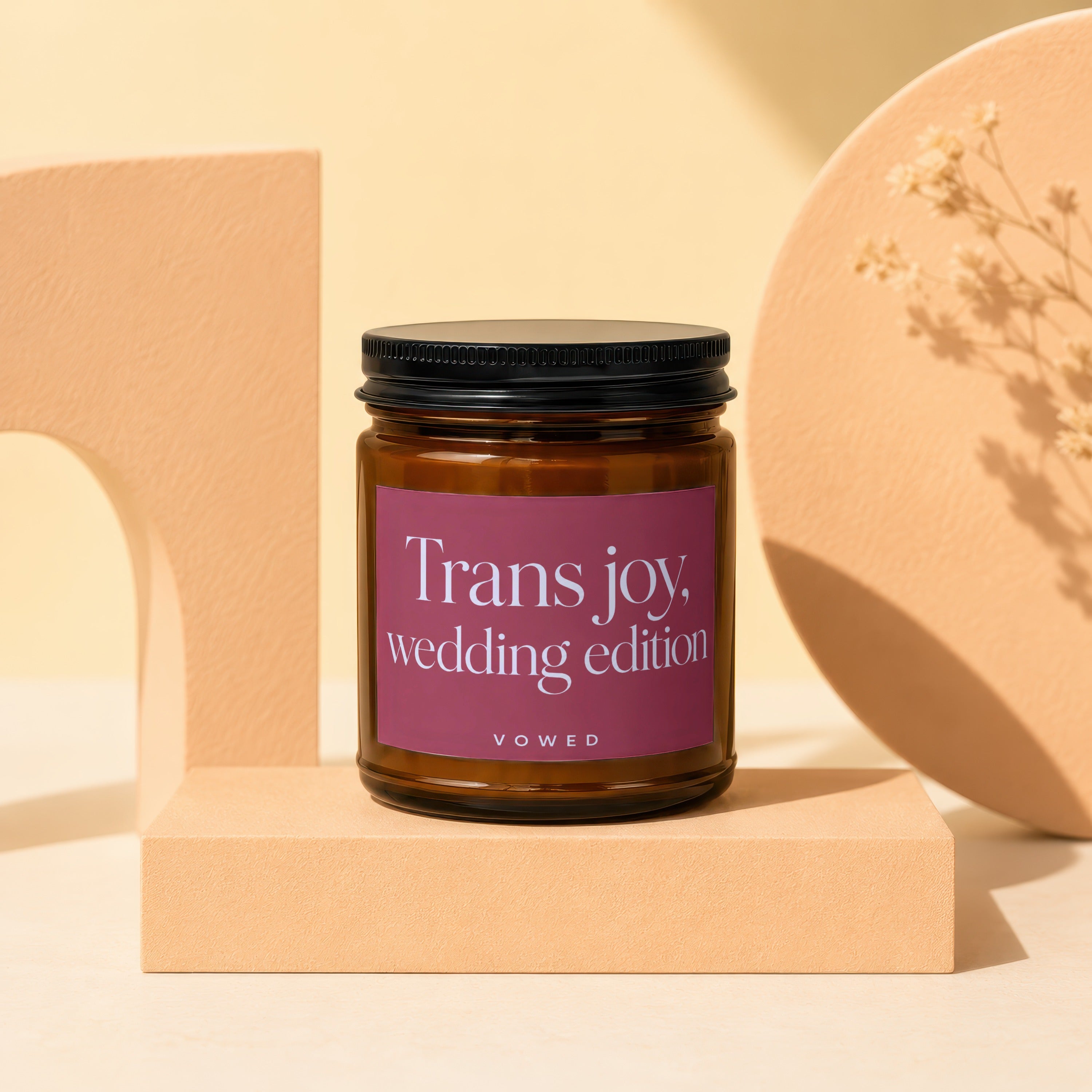 Amber glass candle with maroon label saying "Trans joy, wedding edition".