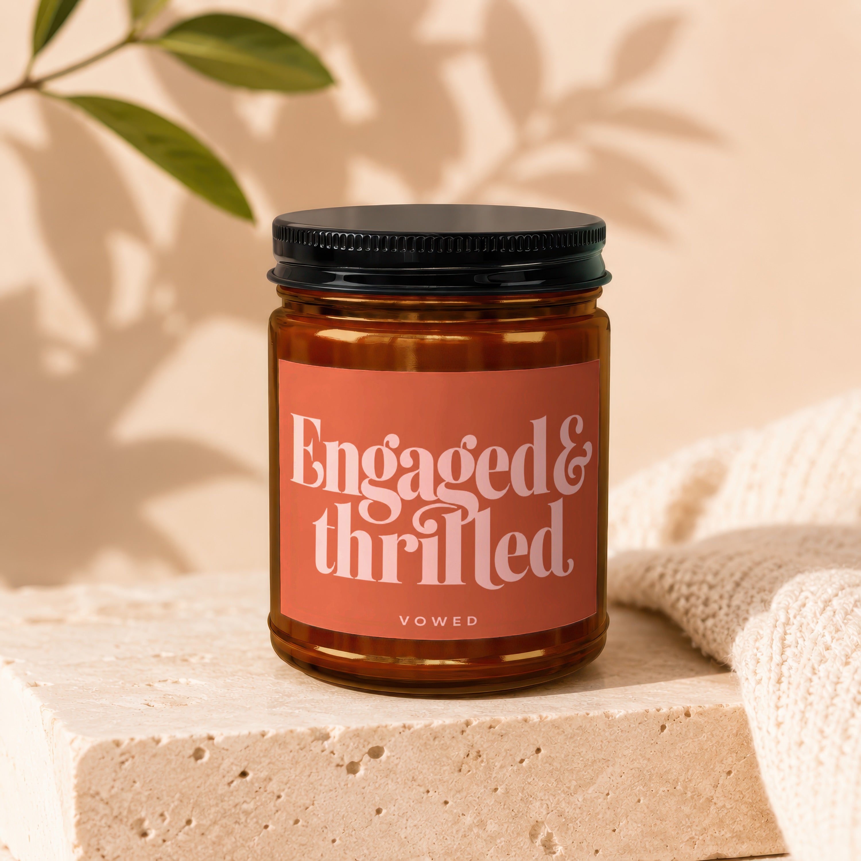 Amber candle in a jar with a black lid, labeled "Engaged & thrilled" and "vowed."