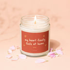 Candle with text "my heart finally feels at home" surrounded by pink petals.