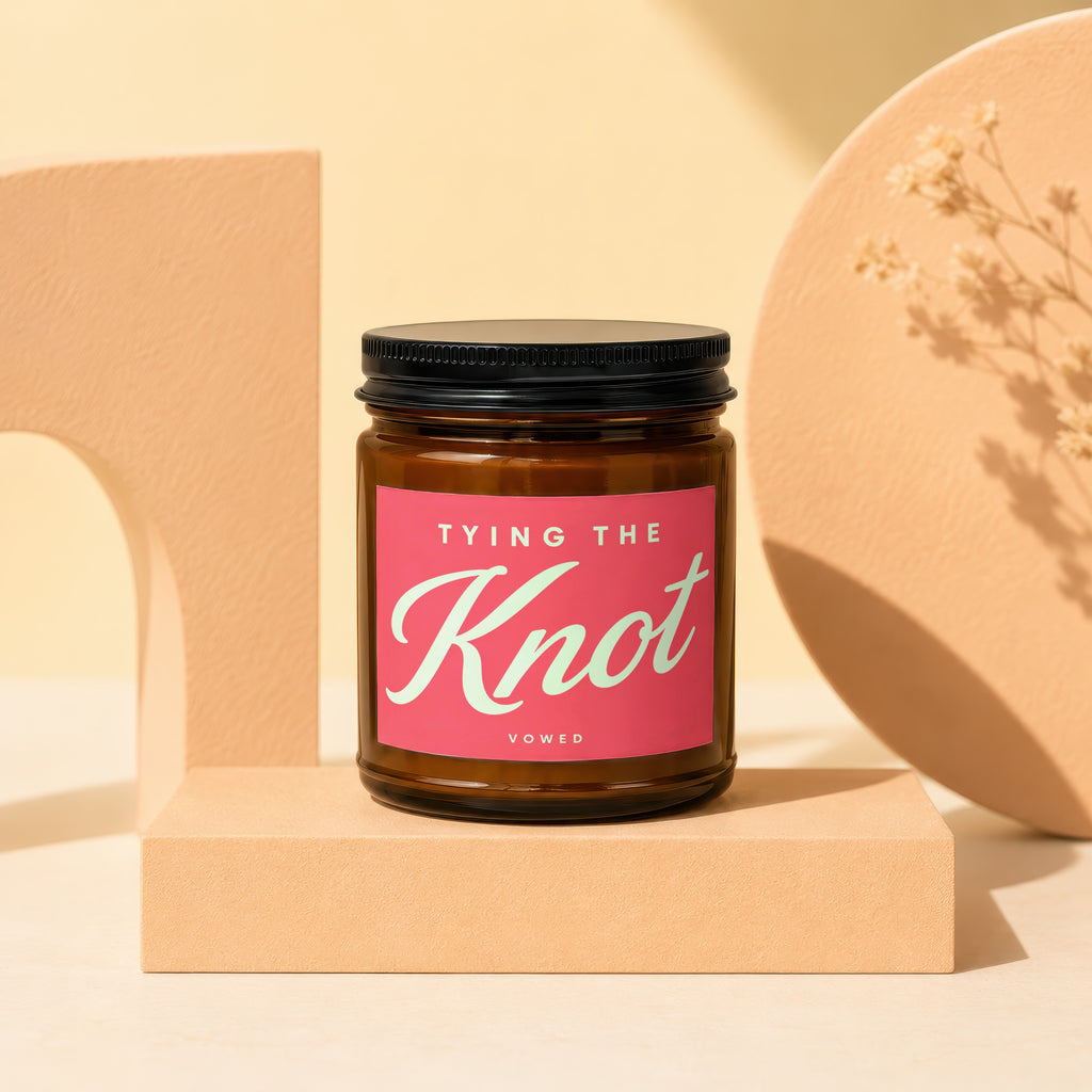 Brown glass candle with pink label reading "TYING THE Knot VOWED."