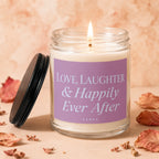 Glass candle with lit flame, a purple label reading "Love, Laughter & Happily Ever After."