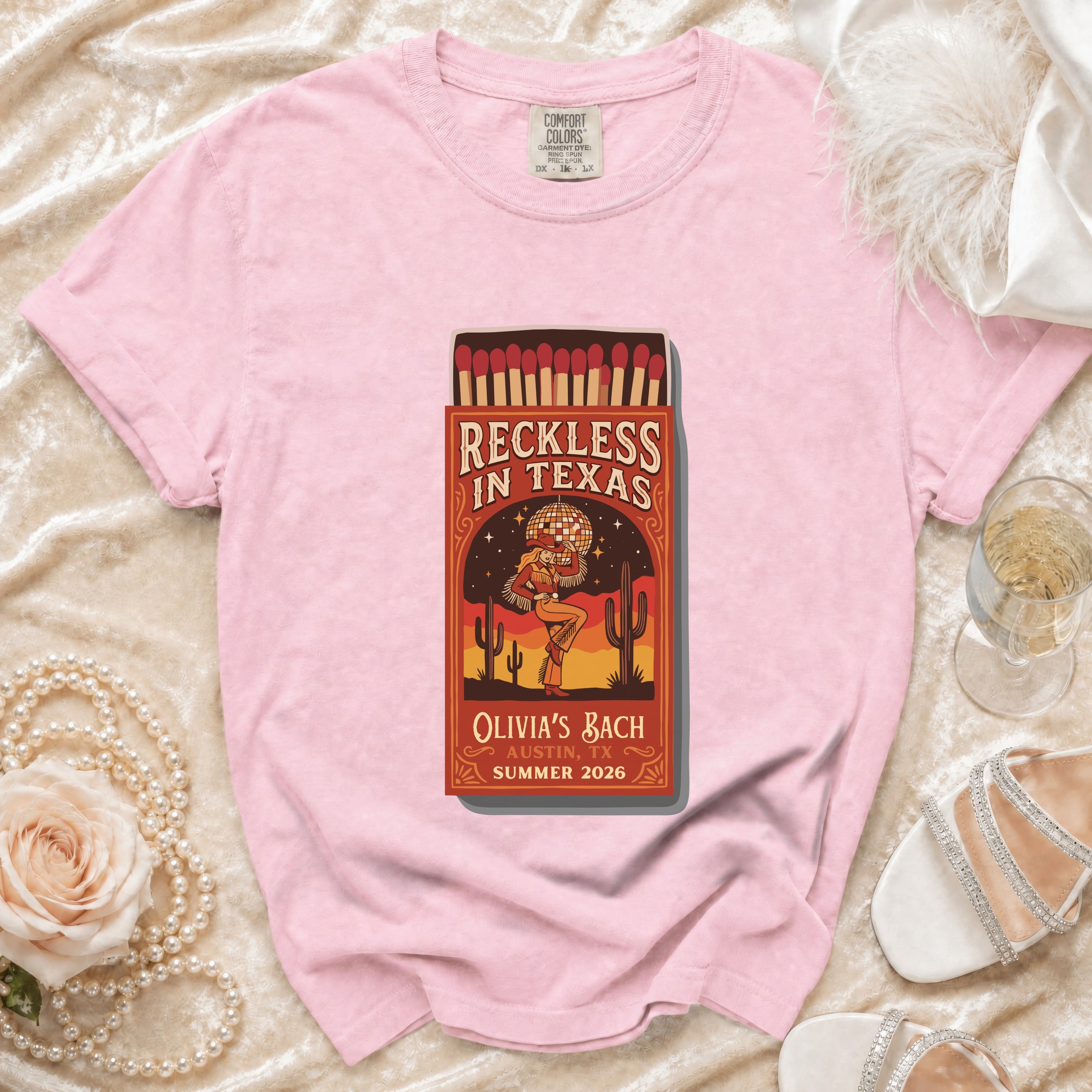 Pink t-shirt with "Reckless in Texas" matchbox graphic and event details.