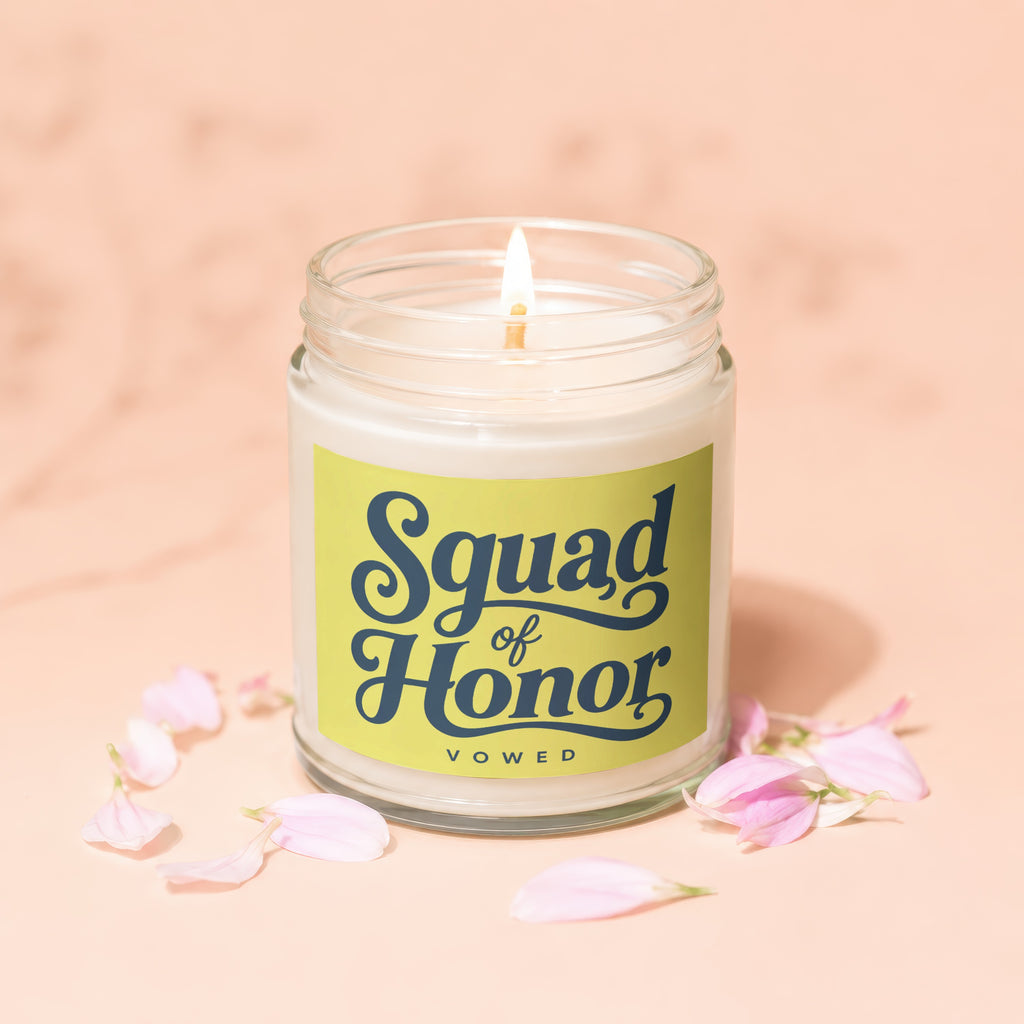 Candle with lit wick and "Squad of Honor VOWED" label surrounded by pink flower petals.