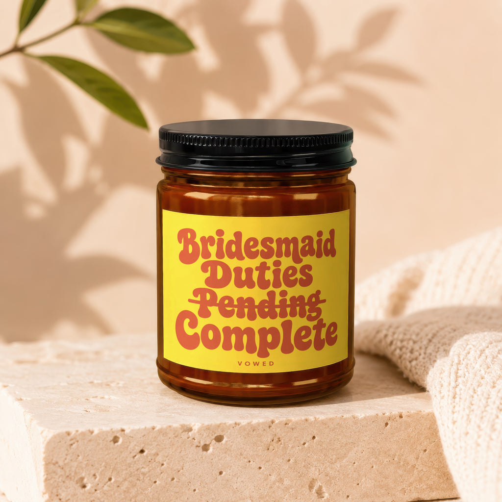 Candle with yellow label reading "Bridesmaid Duties Pending Complete".