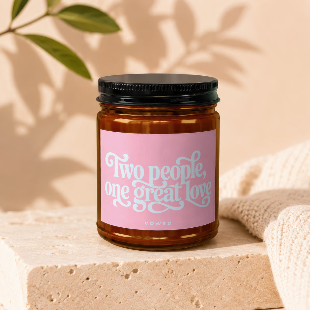 Candle in amber jar with pink label reading "Two people, one great love" and "vowed."