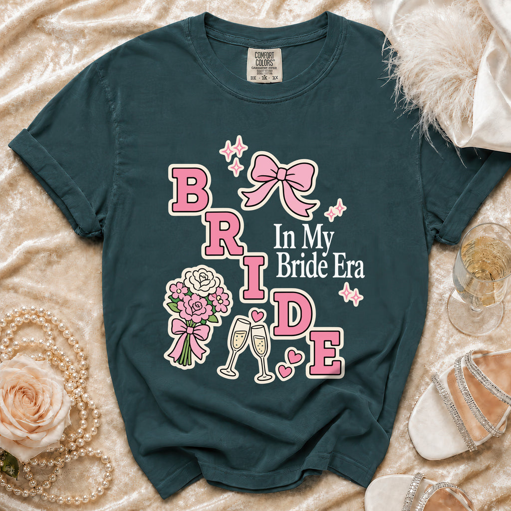 Teal t-shirt with "BRIDE In My Bride Era" graphic, bouquet, champagne glasses and bow.