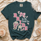 Teal t-shirt with "BRIDE In My Bride Era" graphic, bouquet, champagne glasses and bow.