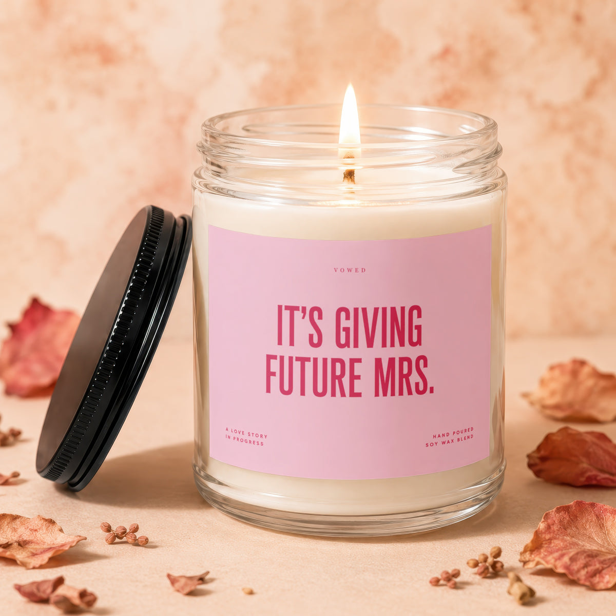 Burning soy wax candle with pink label reading "It's Giving Future Mrs."