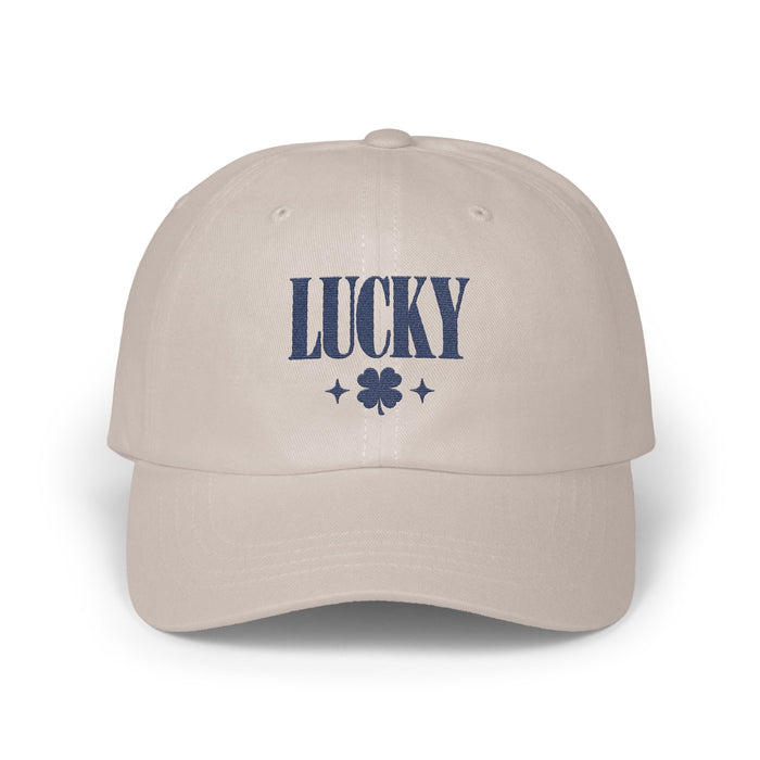 Beige dad hat featuring dark blue embroidered text reading LUCKY above a four-leaf clover.