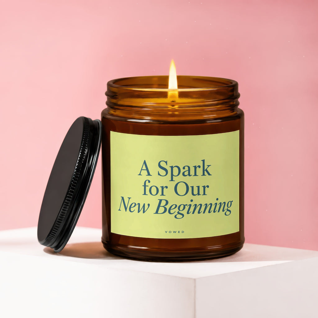 Amber jar candle with lit flame, lid askew. Text "A Spark for Our New Beginning."